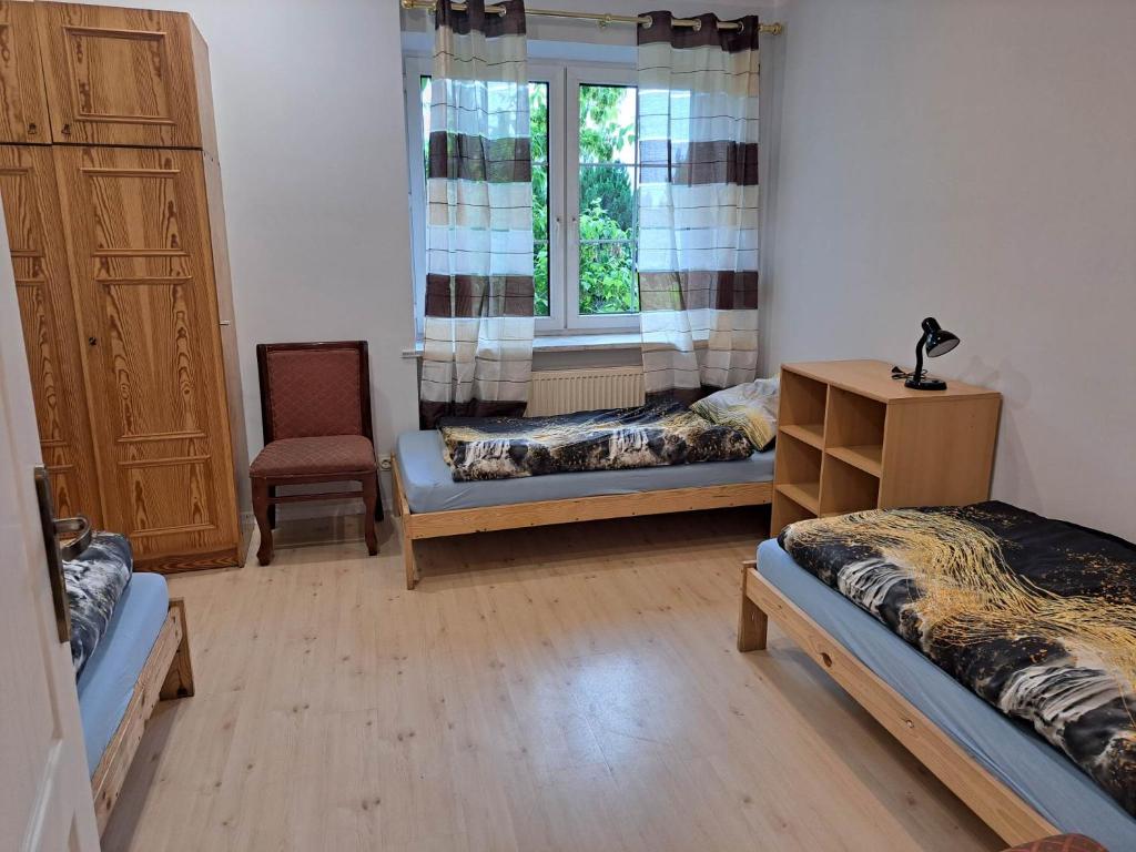 a room with two beds and a window and a chair at Gorzów Wielkopolski Szarych Szeregów 1 wolne Pokoje/kwatery in Gorzów Wielkopolski