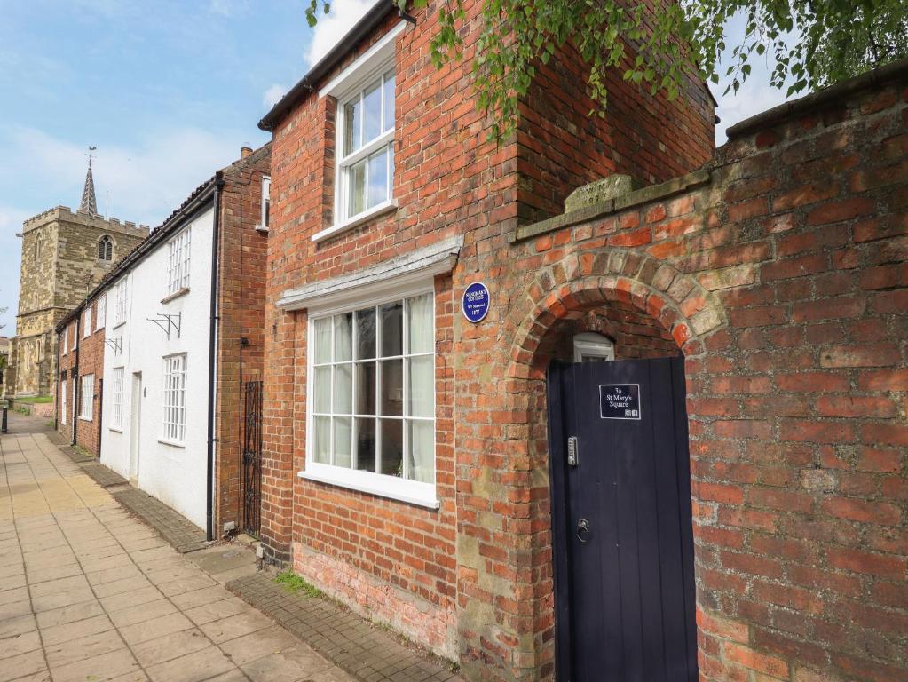 a brick building with a black door on a street at Hangmans cottage in Horncastle