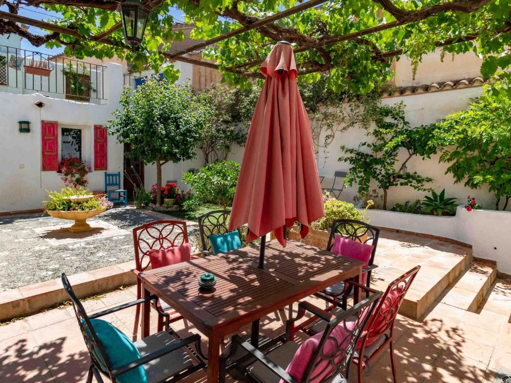 une table en bois avec des chaises et un parapluie rouge dans l'établissement Casa El Sarük, à Nigüelas