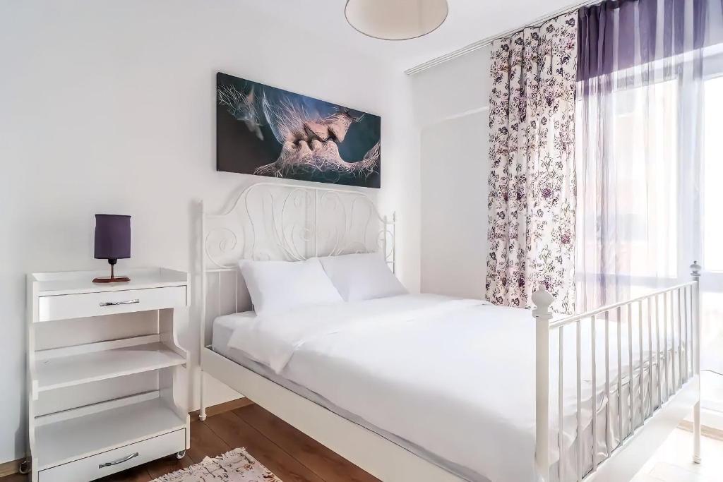 a white bedroom with a bed and a window at Sea and lake view in Maltepe in Istanbul