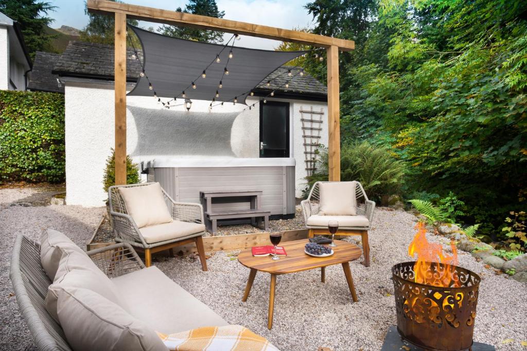 een patio met een bank, stoelen en een tafel bij Bellfoot Rural Retreat and Hot Tub in Grasmere