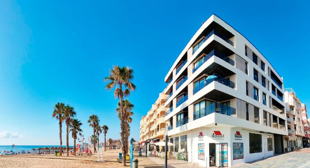un edificio blanco en la playa con palmeras en Luxury Apartment La Mata right by the sea, en La Mata