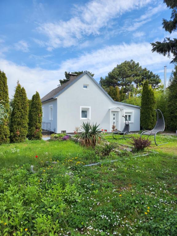 ein weißes Haus mit zwei Bänken im Hof in der Unterkunft HOME 2201 in Gerasdorf bei Wien