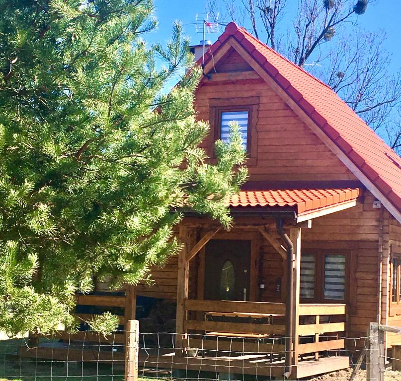 uma cabana de madeira com um telhado vermelho em Domek z bala Mazury em Orzyny