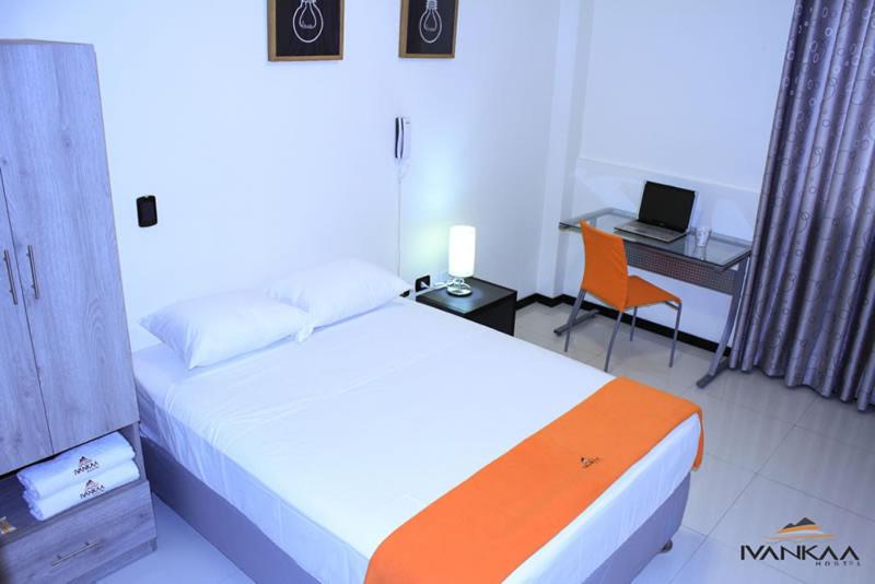 a bedroom with a bed and a desk with a laptop at Ivankaa Hostel in Trujillo