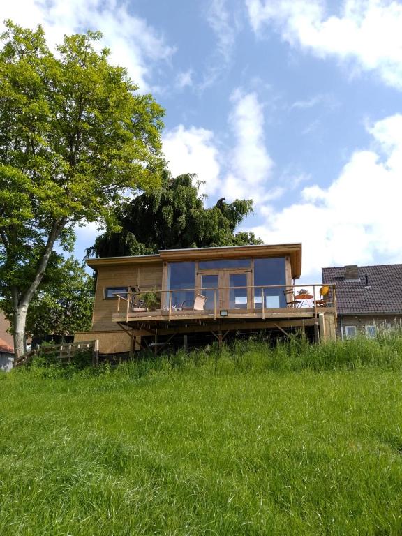 a small house on a field with a tree at The Lodge in Bilzen