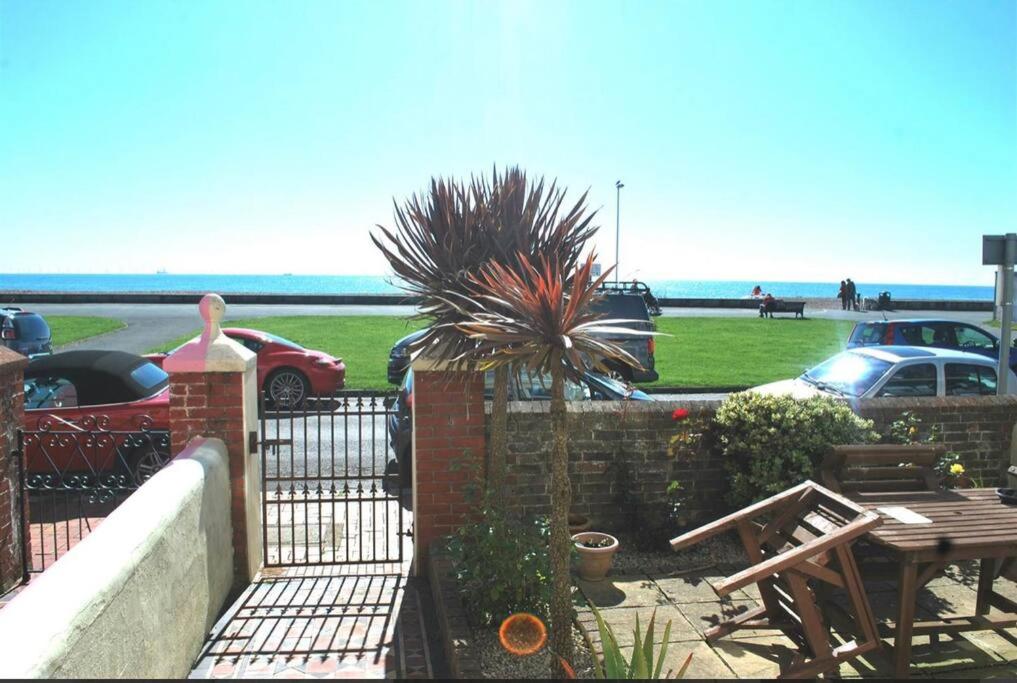a patio with a fence and a table with a palm tree at Stunning seaside studio in Worthing