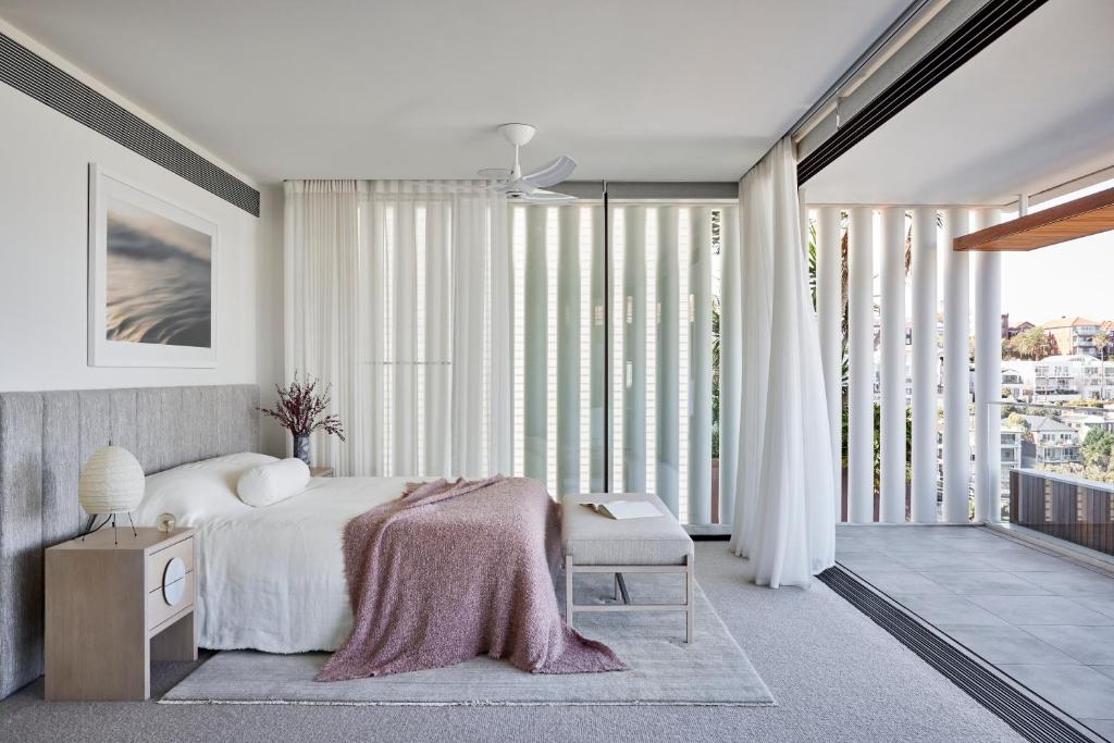 Schlafzimmer mit einem Bett und großen Fenstern in der Unterkunft Casa Tamarama in Sydney