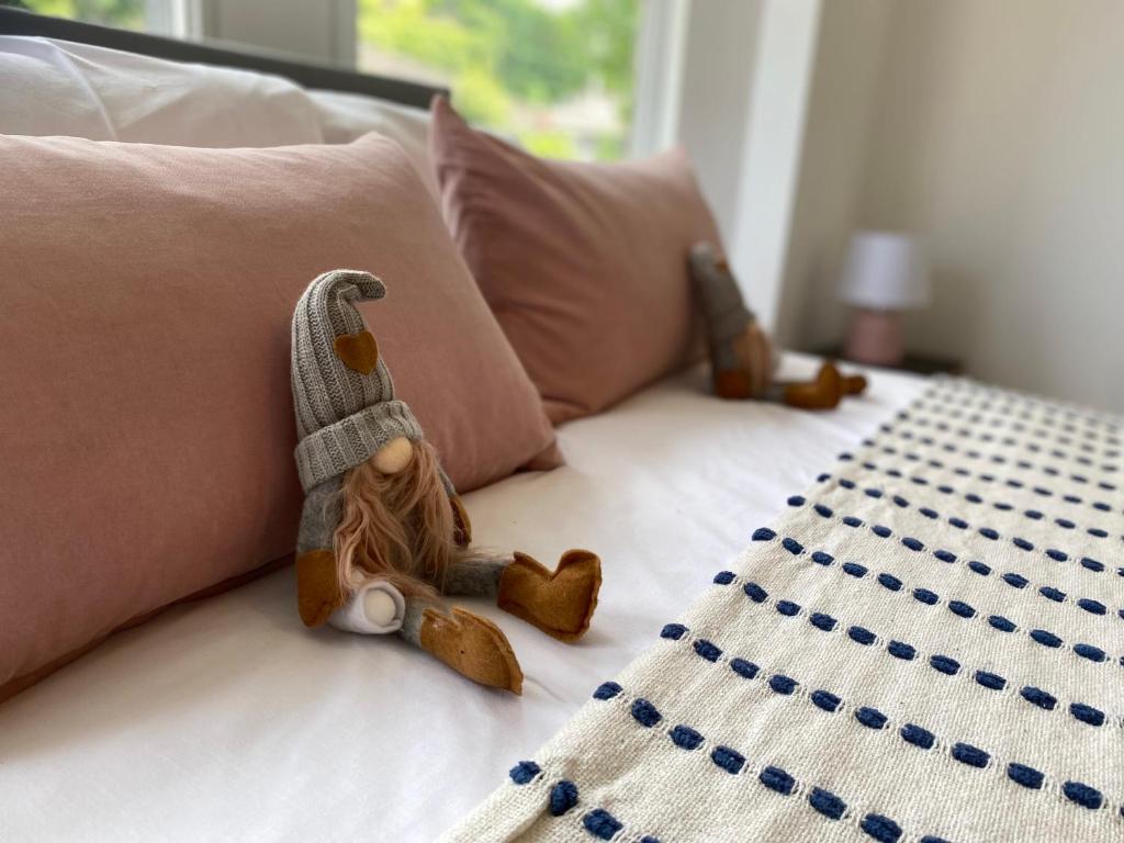 a doll sitting on a bed with two teddy bears at Pentyla by StayStaycations in Port Talbot