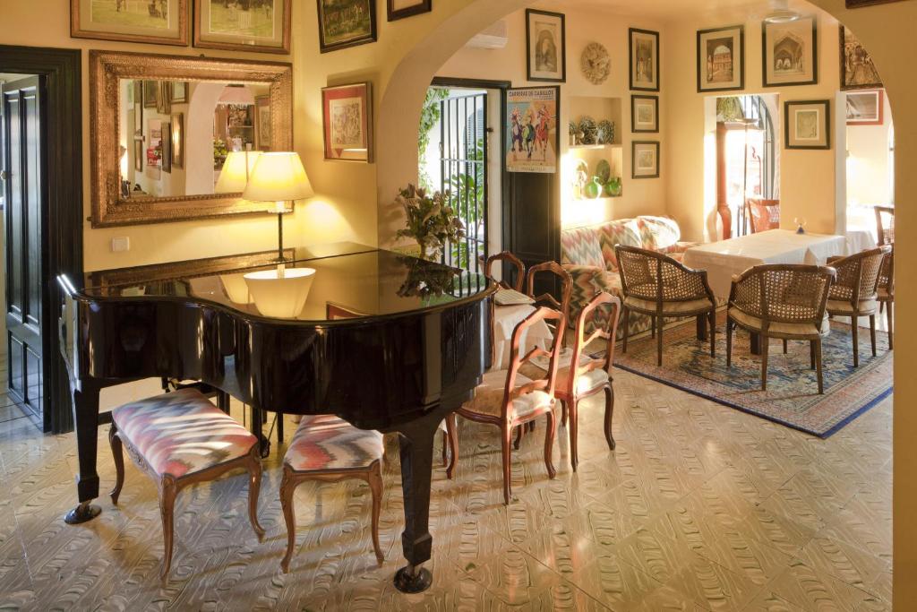 a living room with a piano and a table and chairs at Fowlers Hotel in Cala d´Or