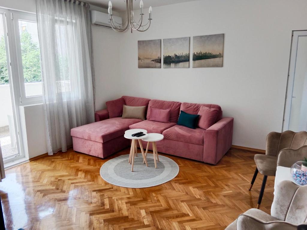 a living room with a pink couch and a table at Serenity City Centre in Podgorica