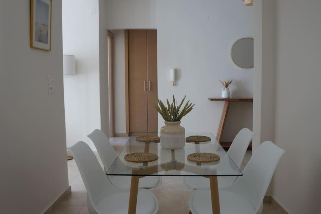 uma sala de jantar com uma mesa de vidro e cadeiras brancas em Central Delight em Chalkida