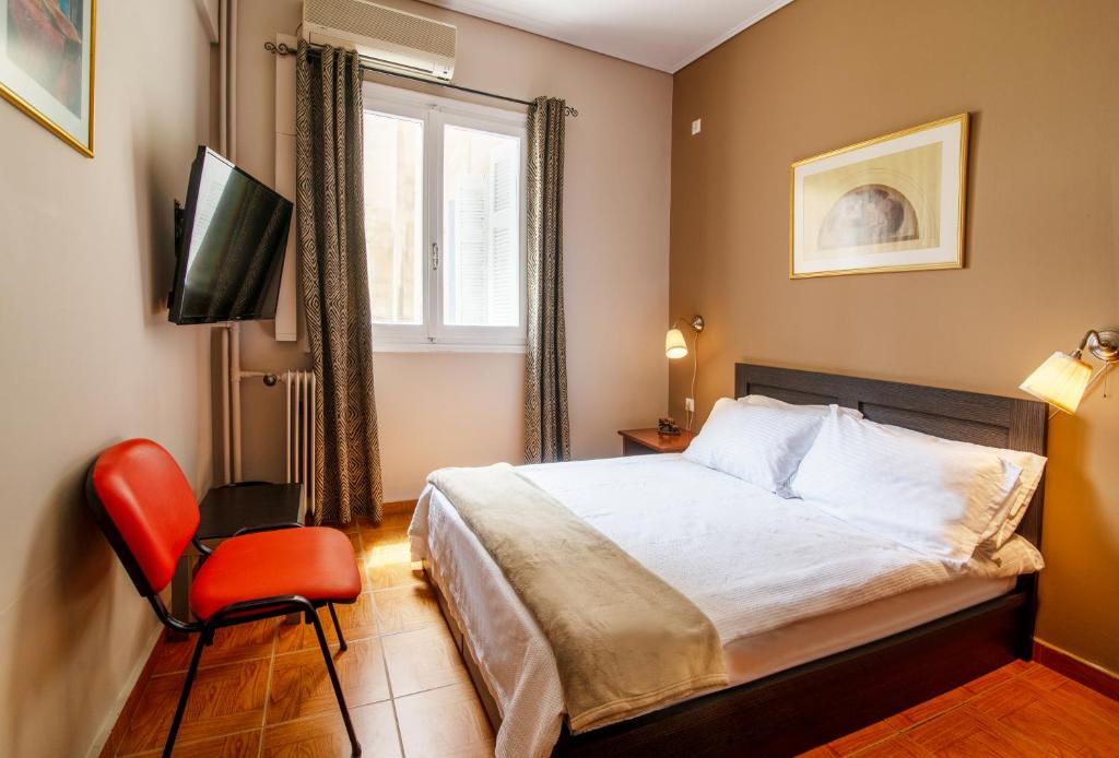 um quarto com uma cama, uma televisão e uma cadeira em Geo city center room em Atenas