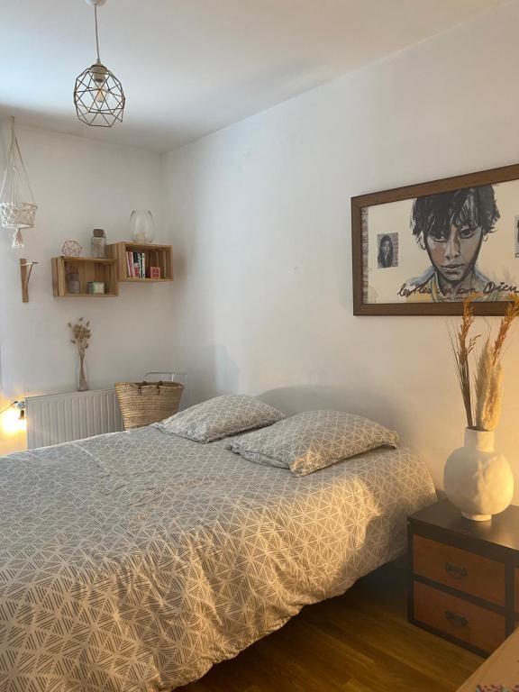 a bedroom with a bed and a painting on the wall at Chambre privée avec SDB attenante in Vertou
