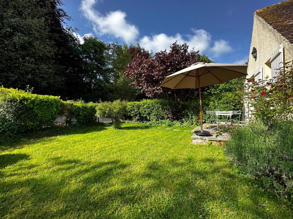 einen Garten mit einem Tisch und einem Sonnenschirm in der Unterkunft Cottage Vesqueville in La Hoguette