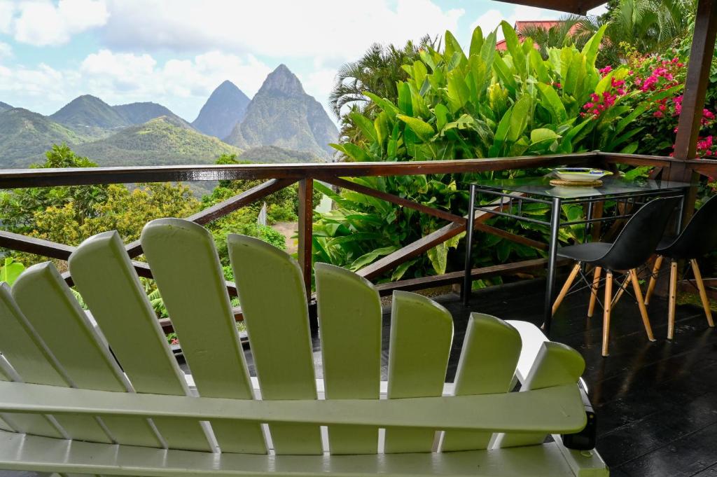 a white chair on a balcony with mountains in the background at The Cottages - Unit 2 in Soufrière