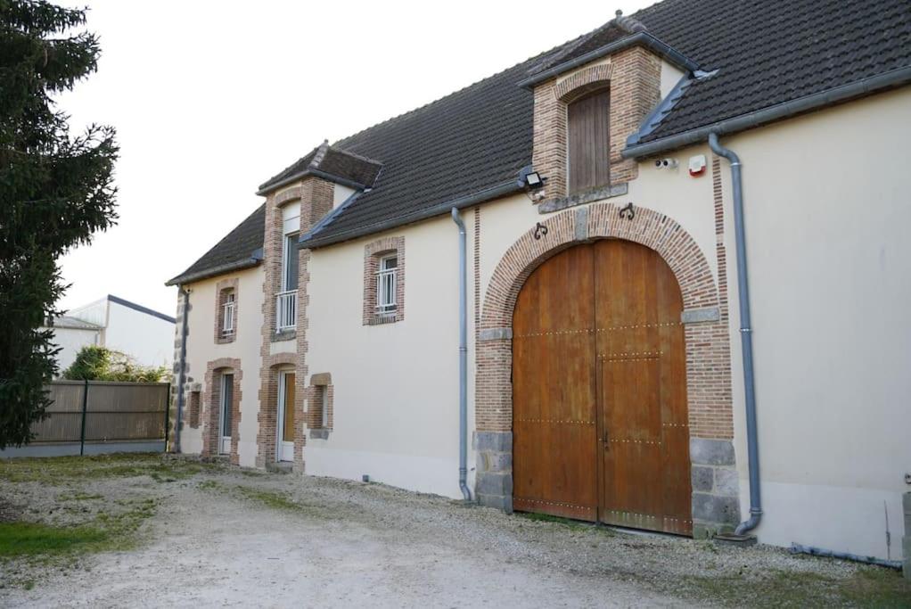 a white house with a wooden garage door at Longère au coeur du vignoble de Champagne in Lachy