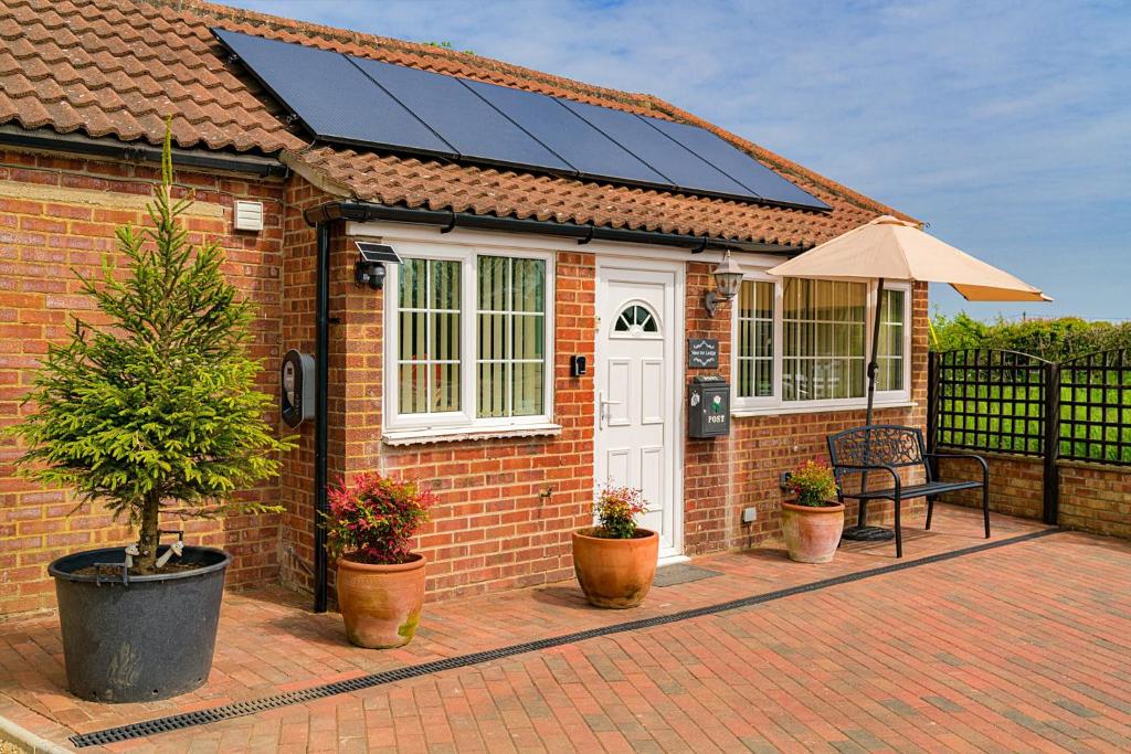 a brick house with solar panels on top of it at Finest Retreats - New Inn Lodge in East Dereham