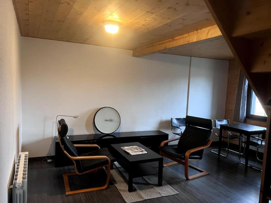 een woonkamer met een tafel en stoelen en een spiegel bij LE BUCHER in Montbéliard