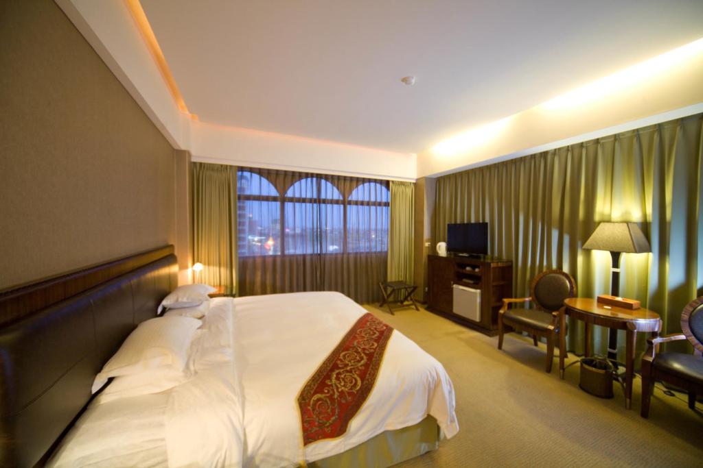 a hotel room with a large bed and a desk at Resort One Hotel in Jiaoxi