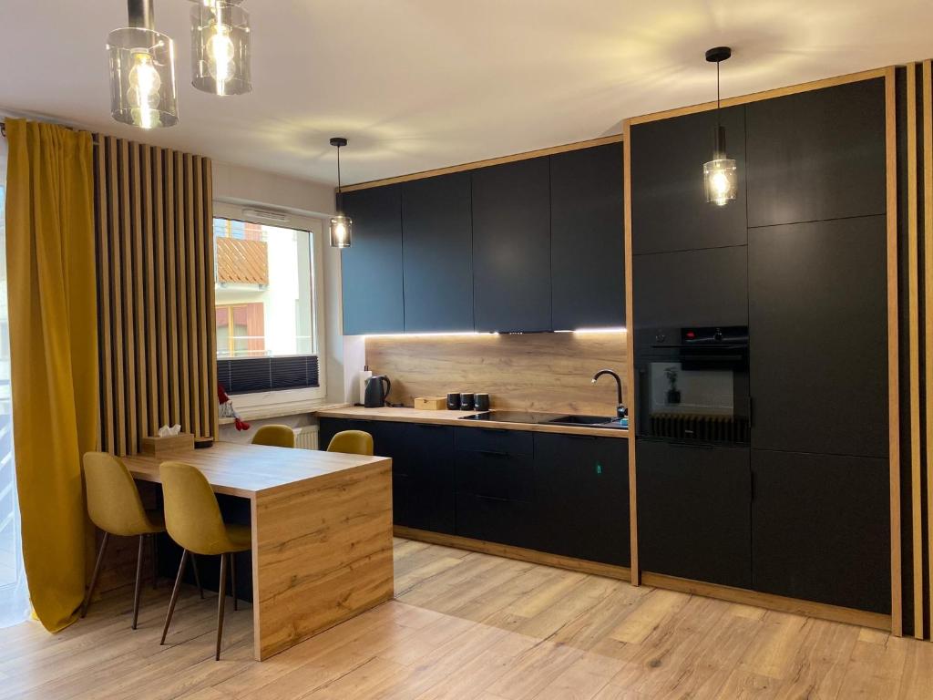 a kitchen with black cabinets and a table and chairs at Apartament Sanok nad stawami in Sanok