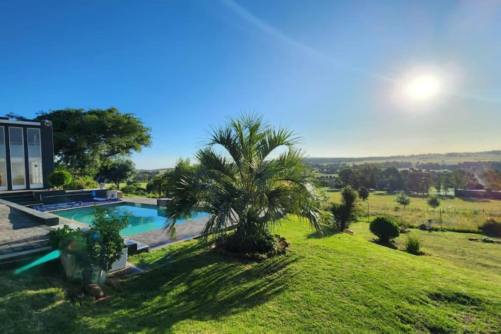 uma palmeira num campo ao lado de uma piscina em RaHa Soul Sanctuary - Entire Home em De Deur