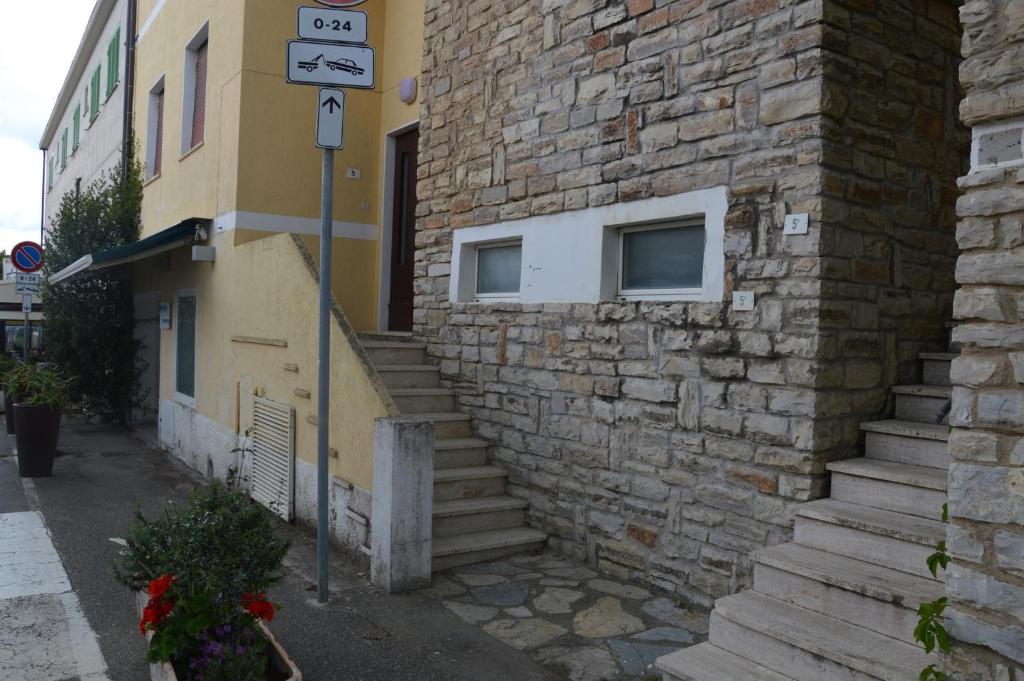a building with a stone wall and a street sign at Alberto Quadrilocale a soli 150m dal mare in Marina di Castagneto Carducci