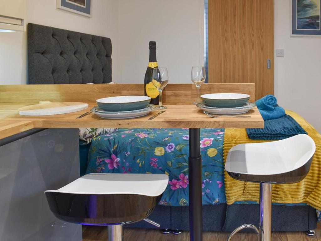 a table with two chairs and a table with plates and glasses at Chyvelyn in Perranporth