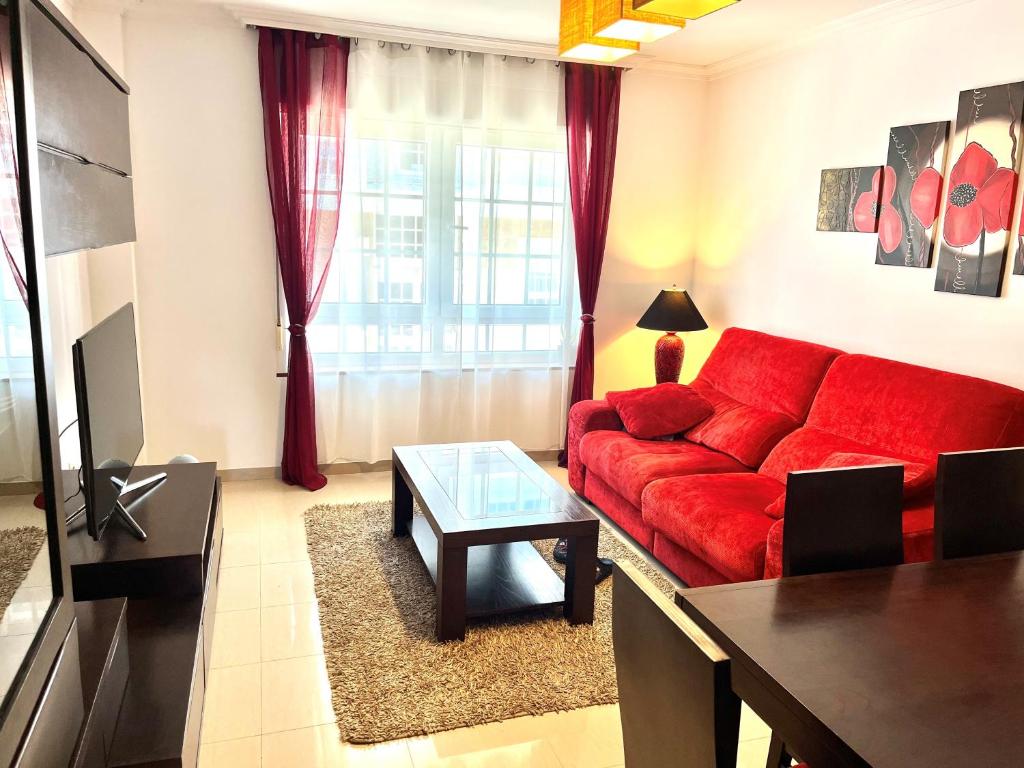 salon z czerwoną kanapą i stołem w obiekcie Apartamento Praia Naval w mieście Isla de Arosa