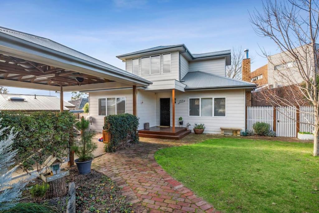 a white house with a brick walkway in a yard at Explore Frankston South from this lovely home in Frankston