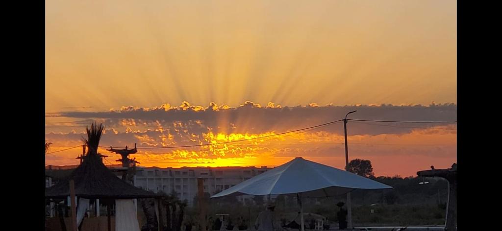 a sunset over a city with a white umbrella at A & H Apartments Velipoje in Velipojë