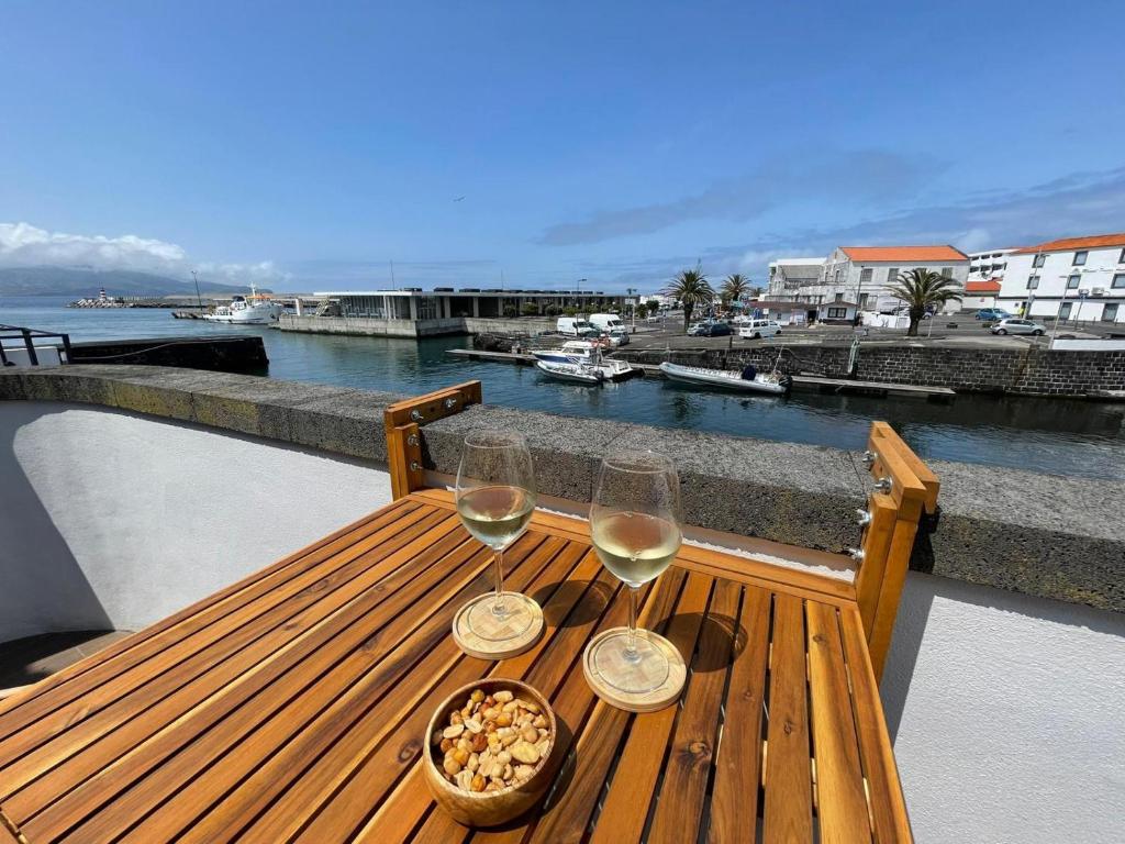 uma mesa de madeira com dois copos de vinho e uma taça de comida em Casa do Porto em Madalena