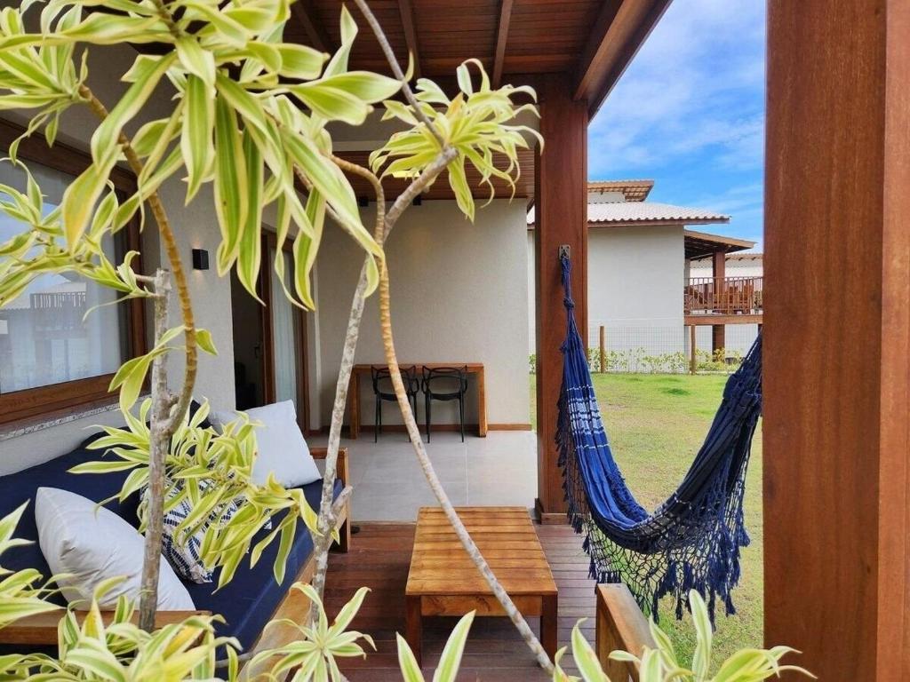 a hammock on the porch of a house at Apartamento Super Charmoso Condomínio OAHU Alto do Imbassaí in Imbassai