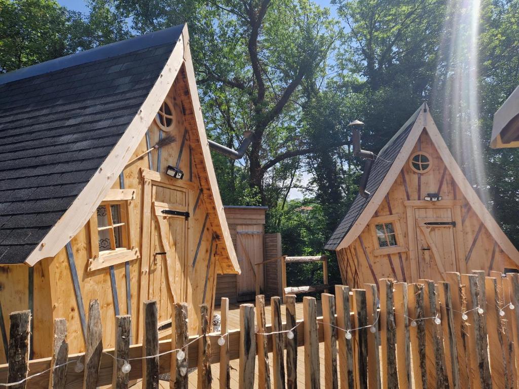 zwei Holzgebäude hinter einem Holzzaun in der Unterkunft Les cabanes féeriques du Cheix in Saint-Diéry