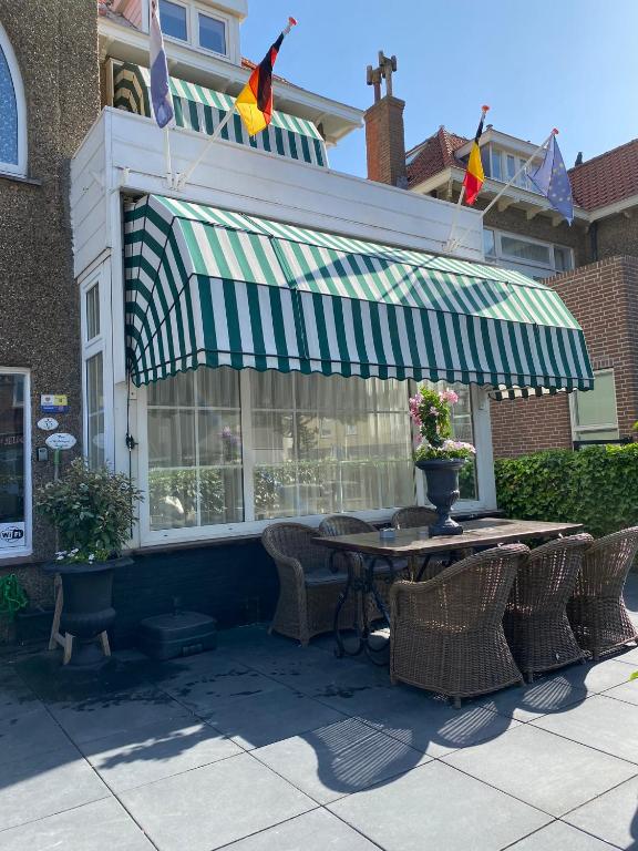 a patio with a table and chairs and flags at Pension Hendriks in Zandvoort