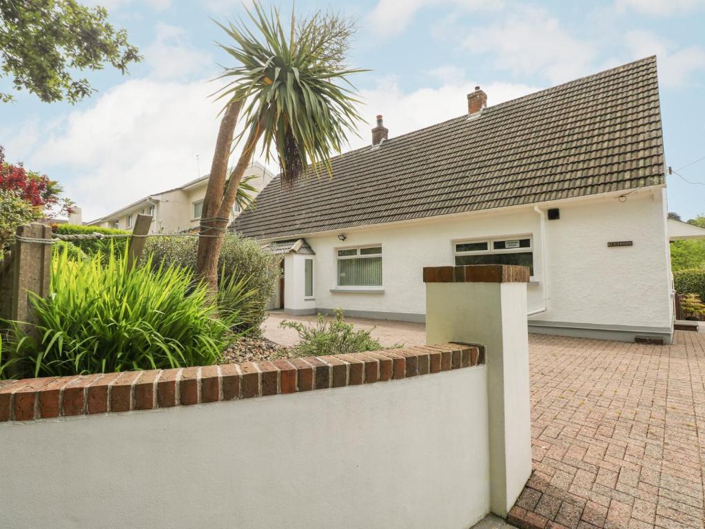 une maison blanche avec une clôture en briques et des palmiers dans l'établissement Ashdown House, à Saundersfoot