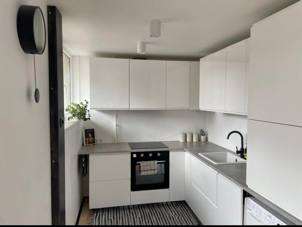 Una cocina blanca con fregadero y estufa. en SEASIDE APARTMENT, en Liepāja