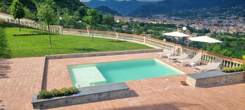 a swimming pool with two chairs and a table and a hill at Villa Marina in Cava deʼ Tirreni