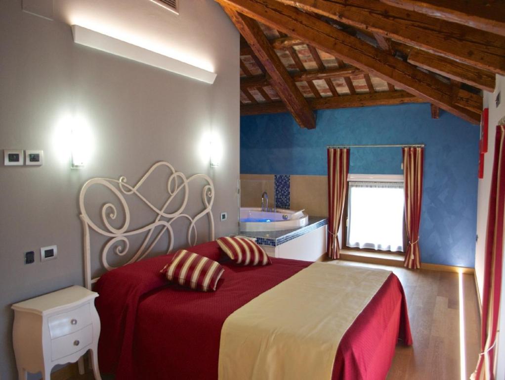 una camera da letto con un letto con lenzuola rosse e una finestra di Villa Butussi - L'ospitalità del Vino a Corno di Rosazzo