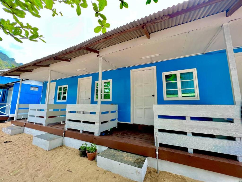 a blue house with a porch in the sand at Khafii Village in Kampong Pasir Panjang
