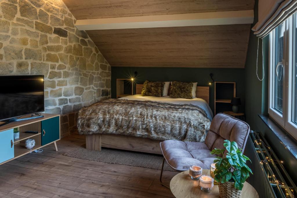 a bedroom with a bed and a stone wall at Le Spalace in Spa