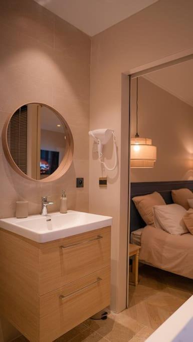 une salle de bain avec un lavabo, un miroir et un lit dans l'établissement Suite de Luxe Jacuzzi balnéo,King size Bed, à Collobrières
