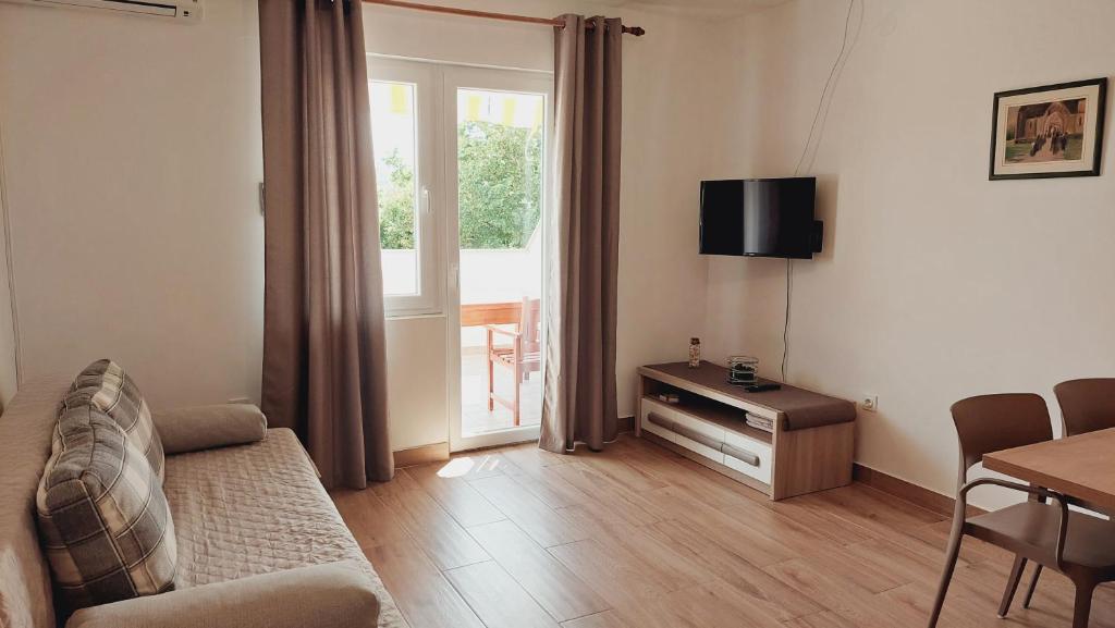 a living room with a couch and a table and a television at Apartments Nikola Caska in Novalja