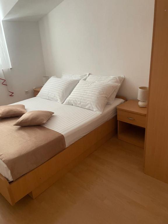 a bedroom with a bed with white sheets and pillows at Apartment Enna in Kaštela