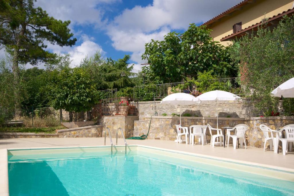 una piscina con sillas blancas y una casa en Madonna del Carmine, en Palazzone