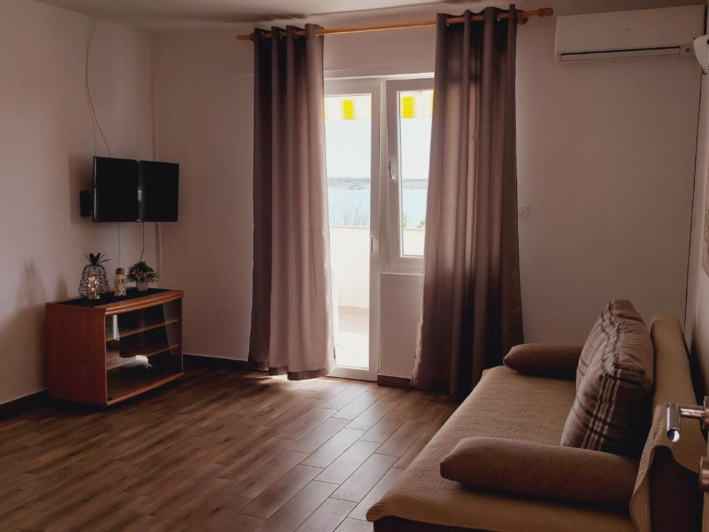 a living room with a couch and a sliding glass door at Apartments Nikola Caska in Novalja