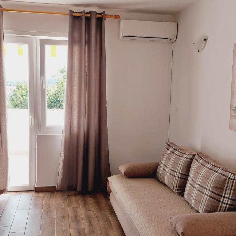 a living room with a couch and a window at Apartments Nikola Caska in Novalja