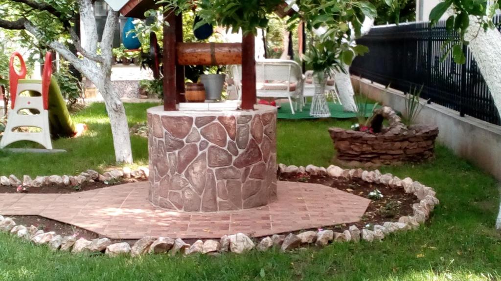 a garden with a stone fountain in the grass at Sobe Milinka in Soko Banja