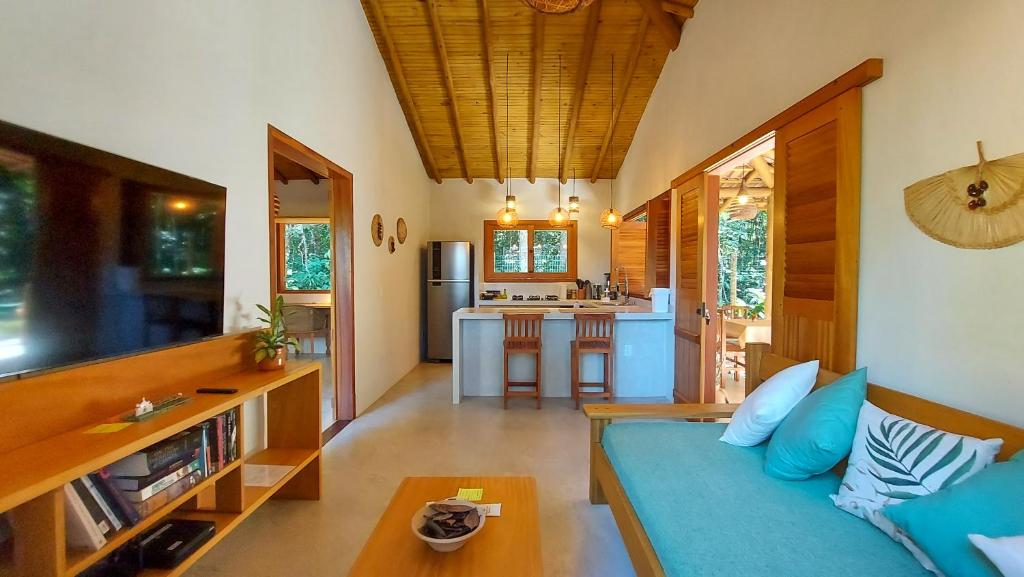 a living room with a blue couch and a kitchen at Vila dos Macacos Trancoso in Trancoso