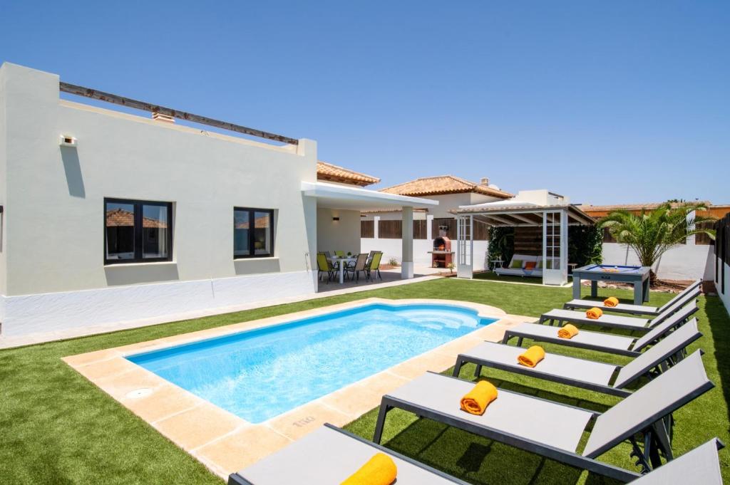 a villa with a swimming pool and lounge chairs at Villa Caleta Heights by Villa Plus in Caleta De Fuste